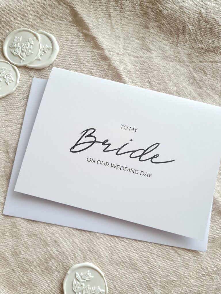 A greeting card with elegant calligraphy that reads "To my Bride on our wedding day". The card has a simple and modern design, with a white background and black text.