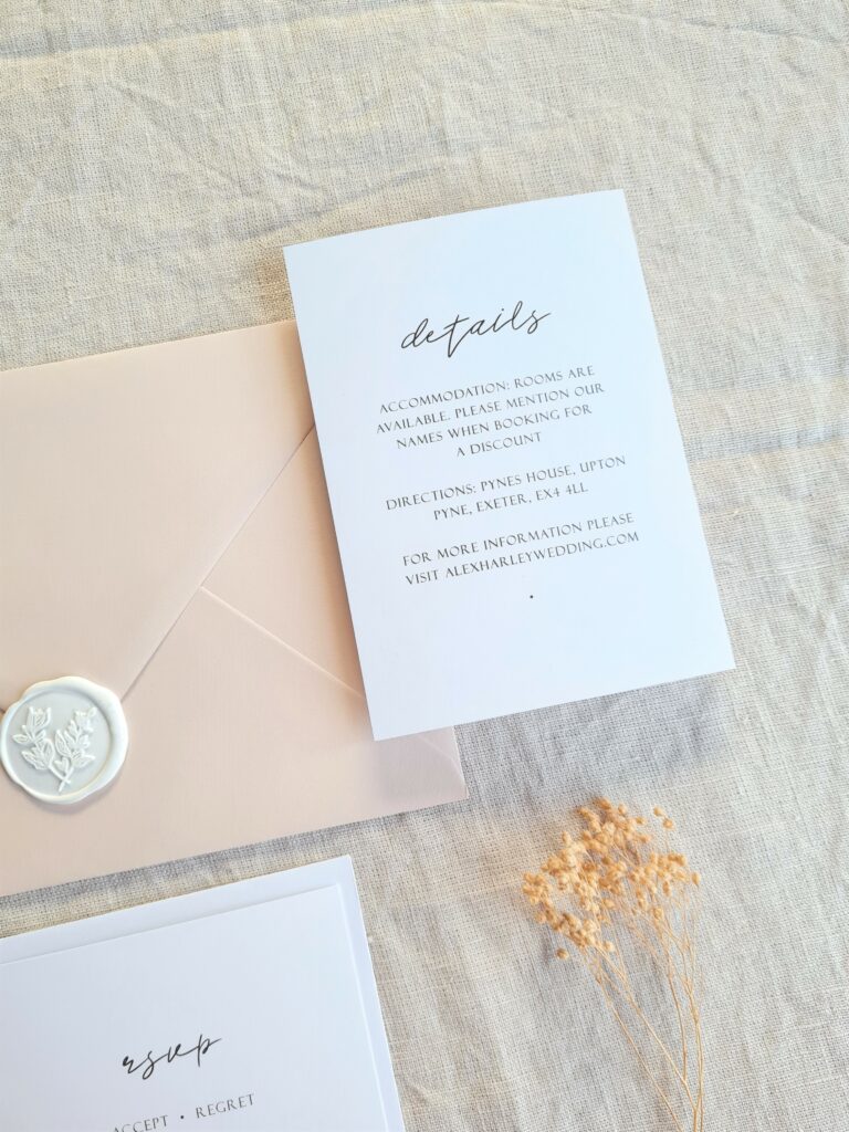 A black and white details card is placed on a beige linen background and is accompanied by natural dried floral elements, white botanical wax seals and a beige envelope. The overall aesthetic is elegant, modern and sophisticated.