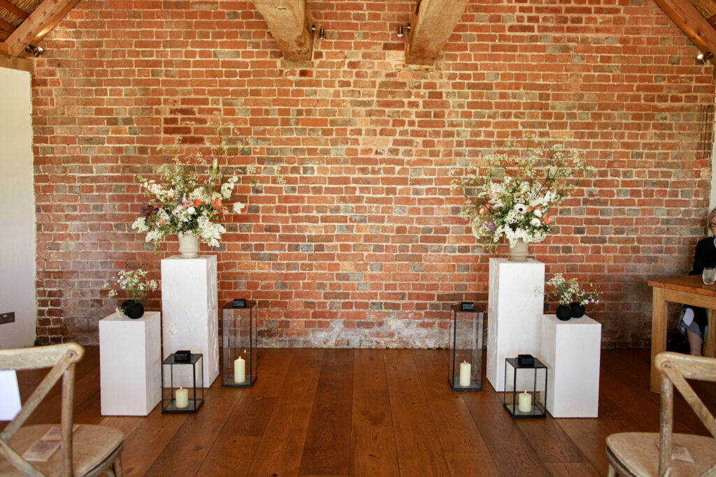 The end of the wedding aisle at Brickhouse Vineyard is adorned with modern monochrome flowers and decorations inside the charming red brick roundhouse. The minimalist and contemporary decor adds a touch of elegance to the rustic surroundings, creating a captivating setting for the wedding ceremony.