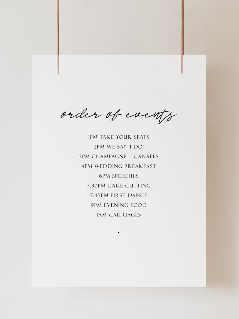 An image of a black and white welcome sign and order of the day sign featuring modern calligraphy-style text. The sign reads "Order of Events" and is hanging on ribbon with a beige background behind.