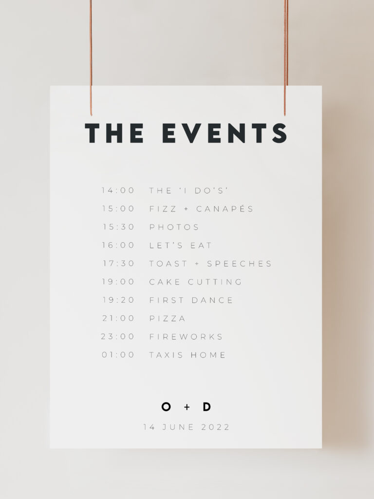 An image of a white wedding Order of the Day sign with modern black text reading "The Events" with times and events listed below. The sign is hanging on ribbon with a beige background behind.