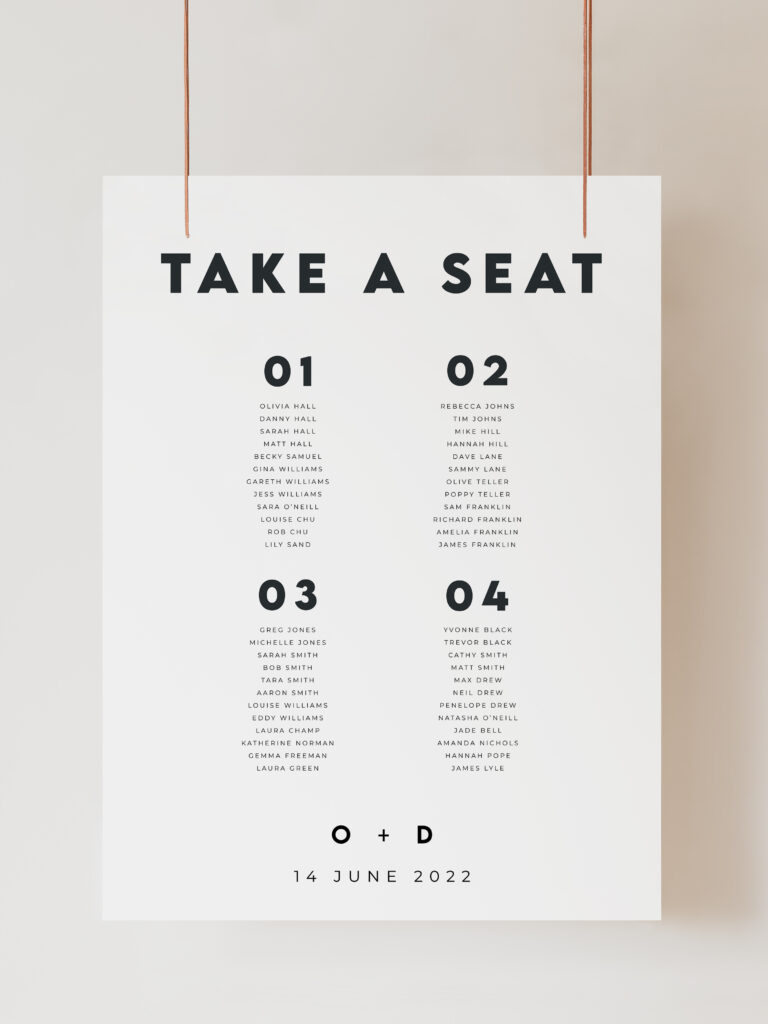 An image of a seating plan sign which is black and white and reads 'take a seat' with table numbers 1-4 below listing guest names for a wedding seating arrangement. The sign is in a modern minimalist style. The sign is hanging on ribbon with a beige background behind.