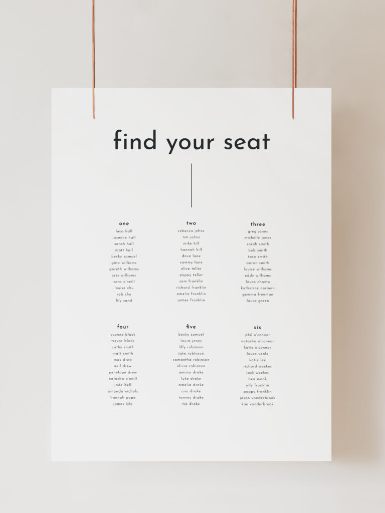 A white wedding table plan sign with modern black text reading "Find Your Seat", followed by a line and then 6 table numbers with guests listed below. The sign is hanging on ribbon with a beige background behind.